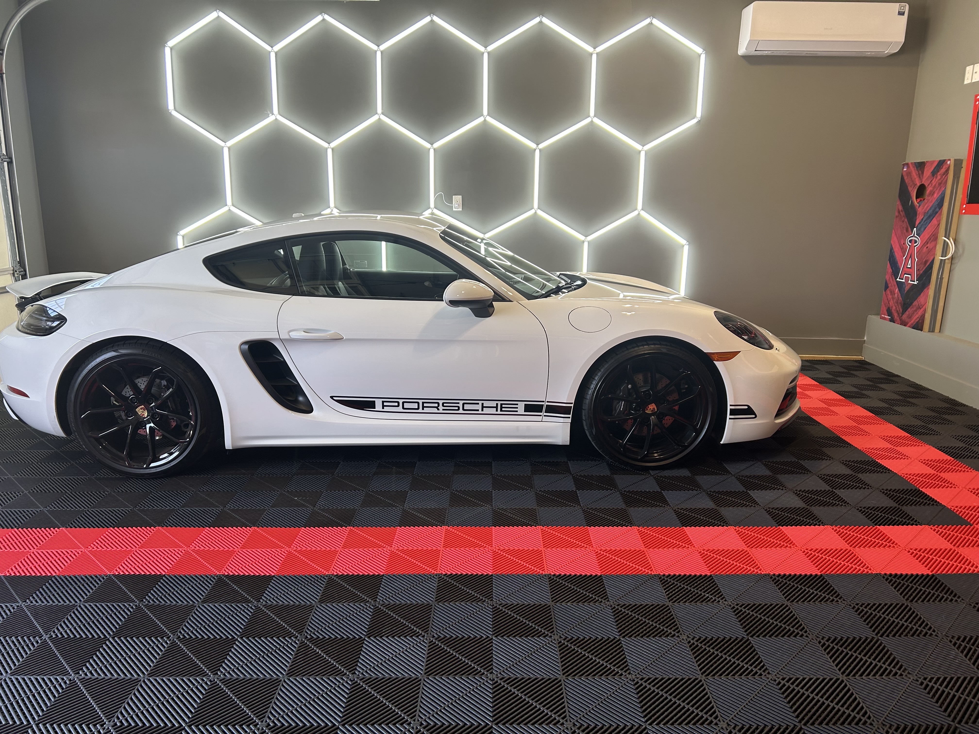 Premium garage with white Porsche, hexagonal LED lighting, and custom black and red checkered flooring